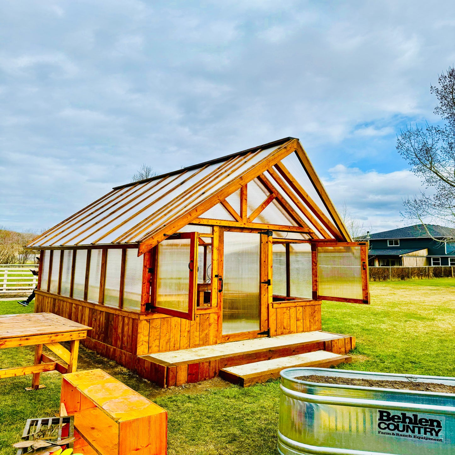 Greenhouse equipped with a hinged door and roof vents for improved airflow and temperature control