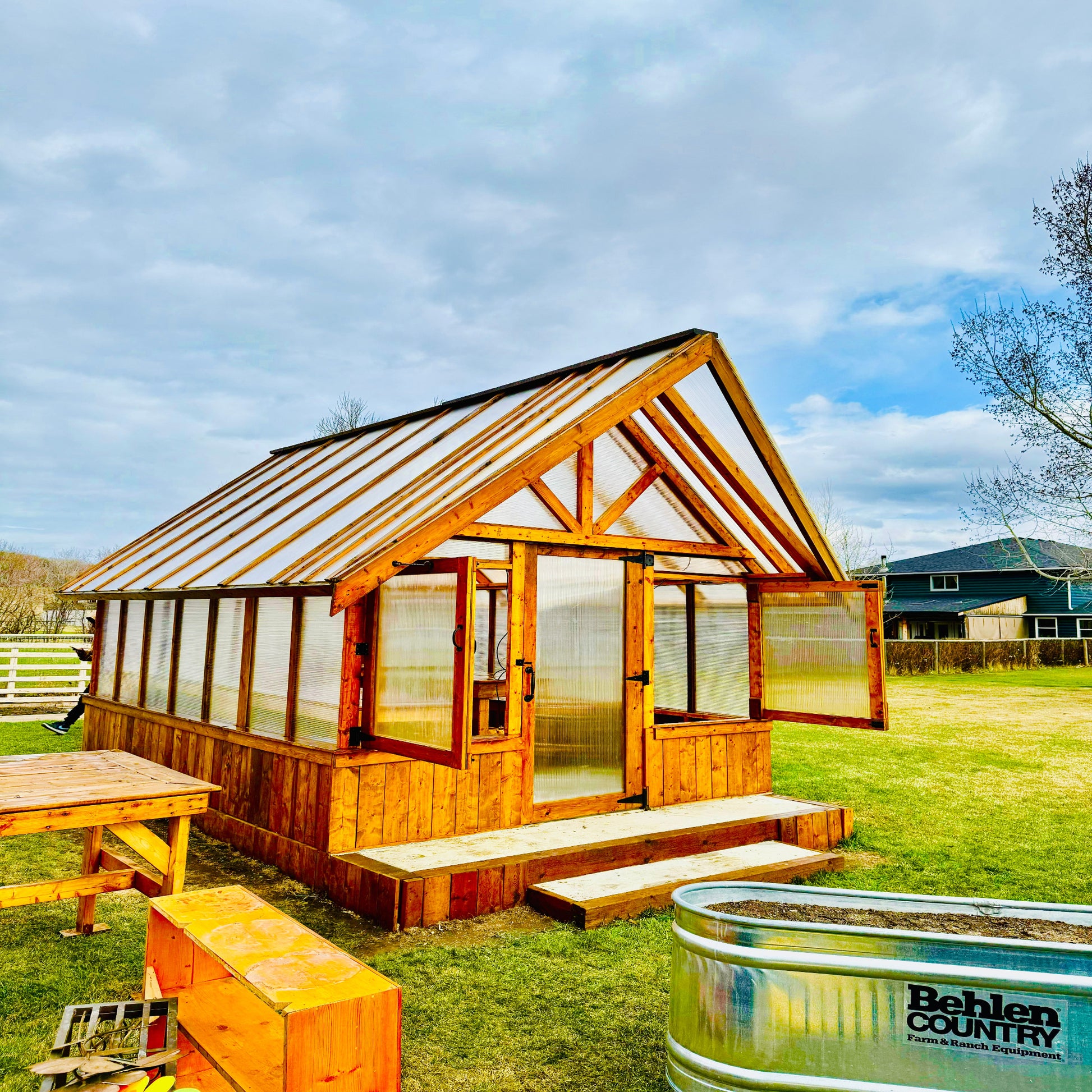 Greenhouse equipped with a hinged door and roof vents for improved airflow and temperature control